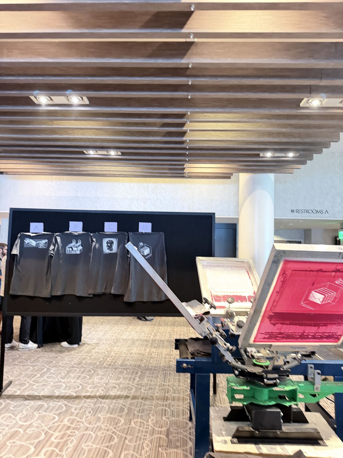 Professional booth setup with tiered display of decorated apparel samples and branded signage